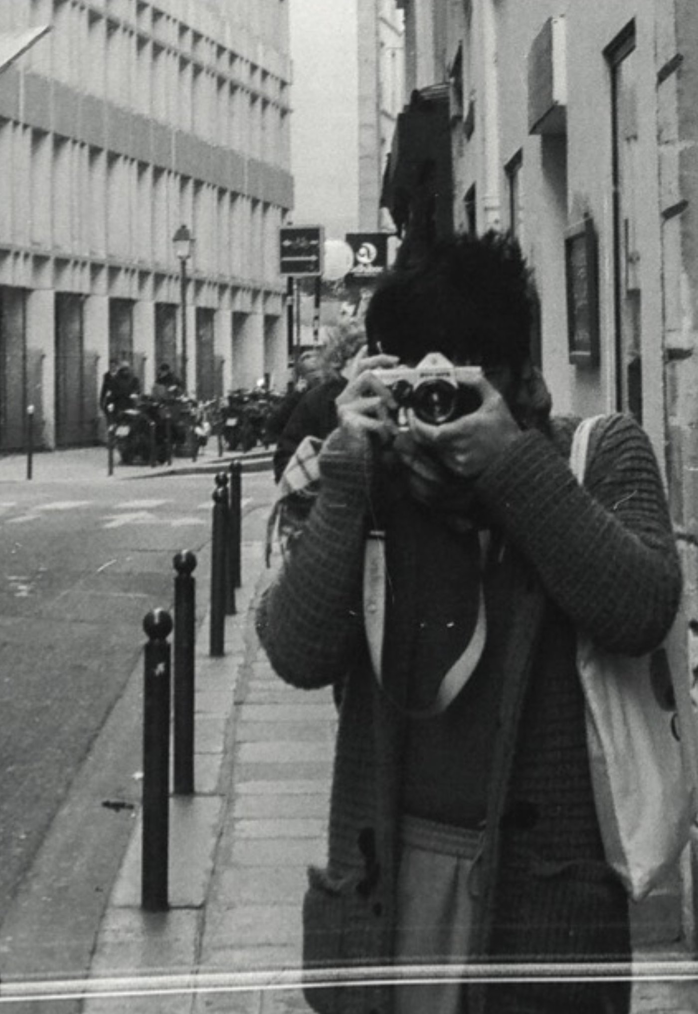 Robert Nguyen taking a photo of himself with a film camera in a Paris street